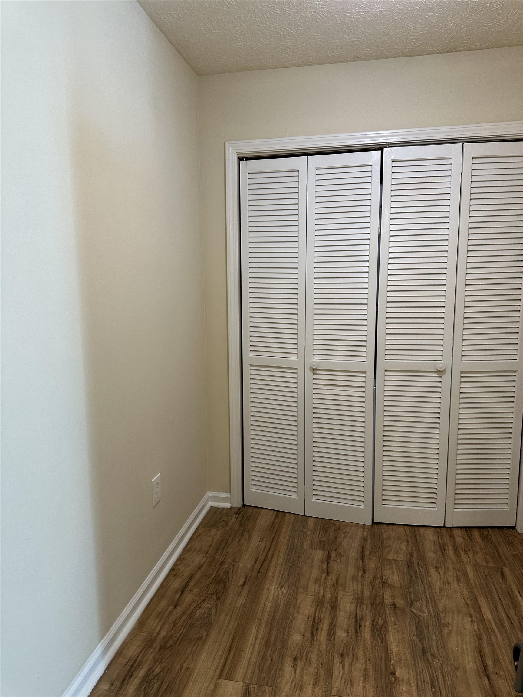 420 Pine Avenue Murrells Inlet, SC 29576 - Photo 16 of 21 Unfurnished bedroom featuring dark wood-style floors, a closet, and a textured ceiling