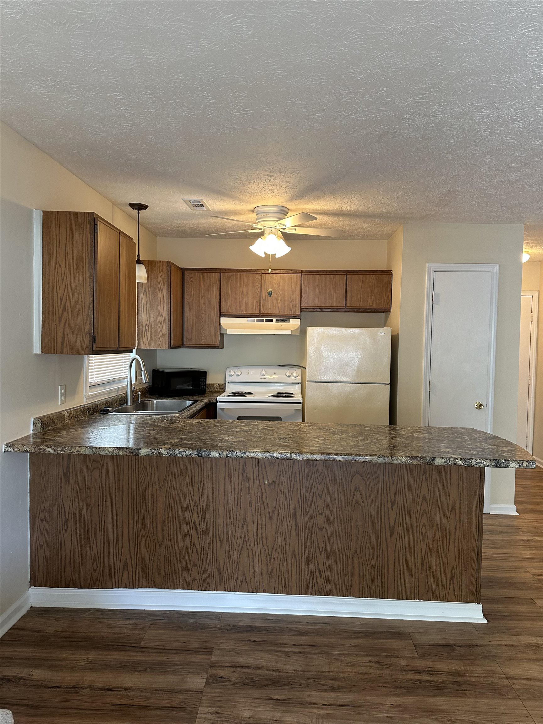 420 Pine Avenue Murrells Inlet, SC 29576 - Photo 9 of 21 Kitchen with dark countertops, white appliances, a peninsula, dark wood-style floors, and a textured ceiling