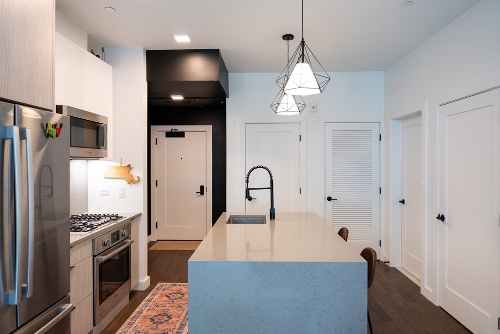 2 Sinclair Road, Unit 202 Boston, MA 02134 - Photo 4 of 23 a large kitchen with stainless steel appliances a refrigerator a stove a sink dishwasher and a stove with wooden floor