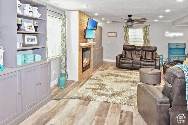 1500 Fish Creek Road Bancroft, ID 83217 - Photo 25 of 45 Living room featuring light wood-type flooring, a textured ceiling, a fireplace, a ceiling fan, and recessed lighting