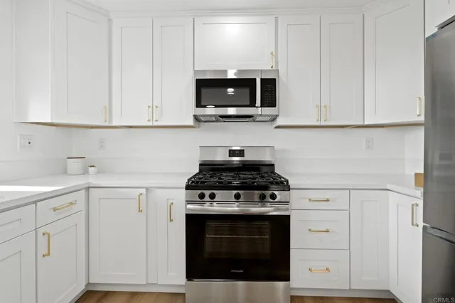 a kitchen with white cabinets and stainless steel appliances