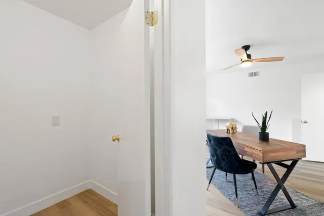 an empty room with wooden floor fan and windows