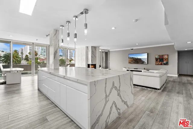 a large white kitchen with kitchen island a stove a sink a refrigerator and white cabinets with wooden floor