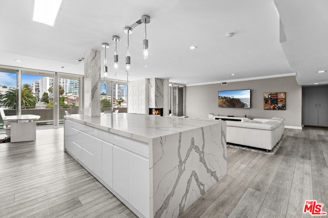 a large white kitchen with kitchen island a stove a sink a refrigerator and white cabinets with wooden floor