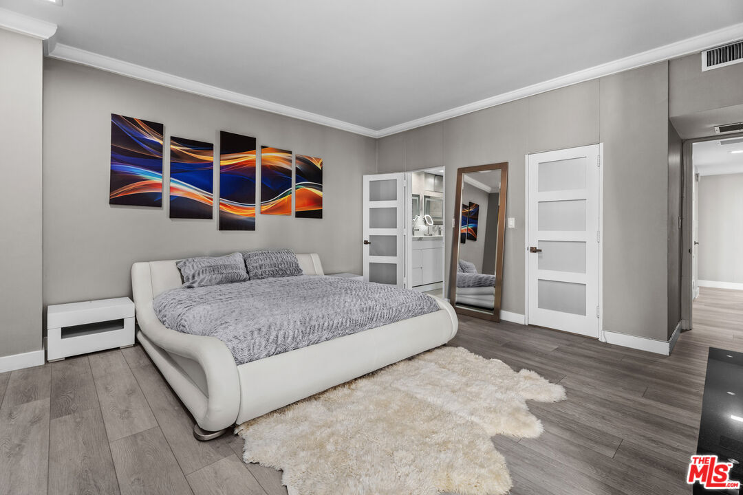 1333 South Beverly Glen Boulevard, Unit 605 Los Angeles, CA 90024 - Photo 13 of 27 a bedroom with a large bed and a chandelier