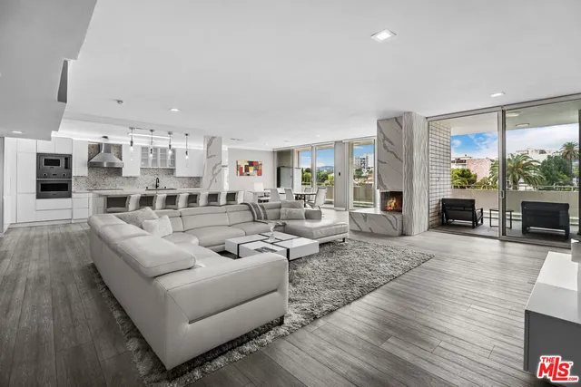 a living room with furniture kitchen view and a wooden floor
