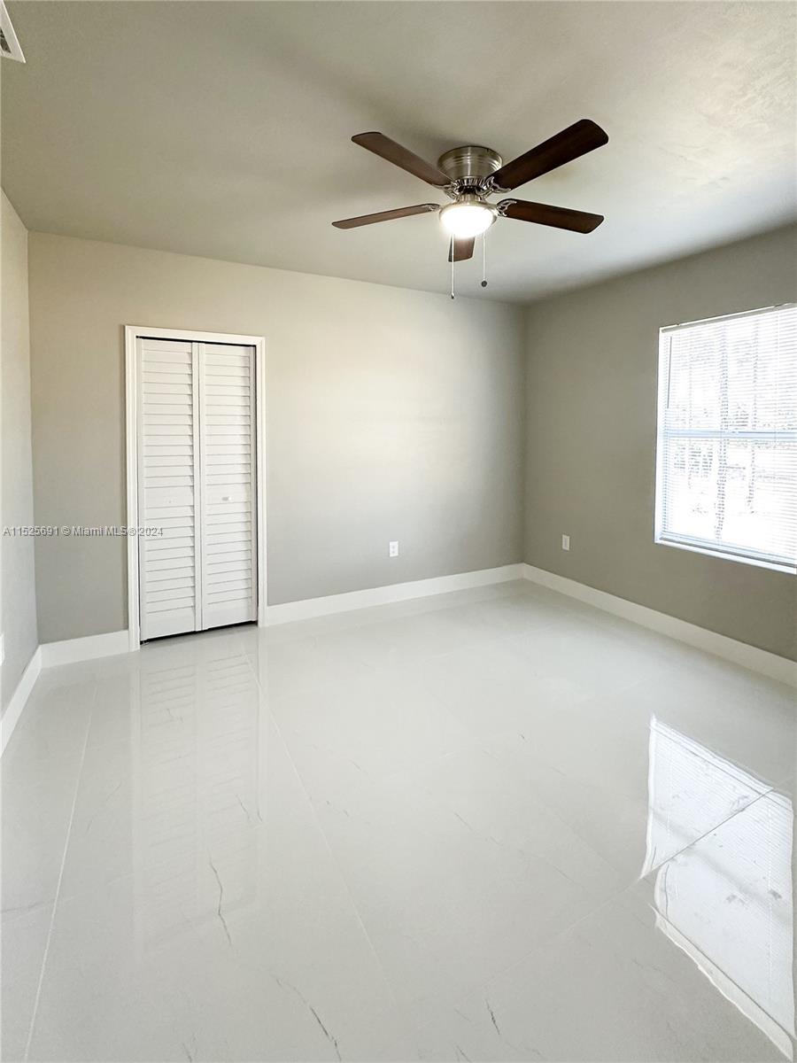 828 Homestead Road South Lehigh Acres, FL 33974 - Photo 19 of 48 an empty room with windows and ceiling fan