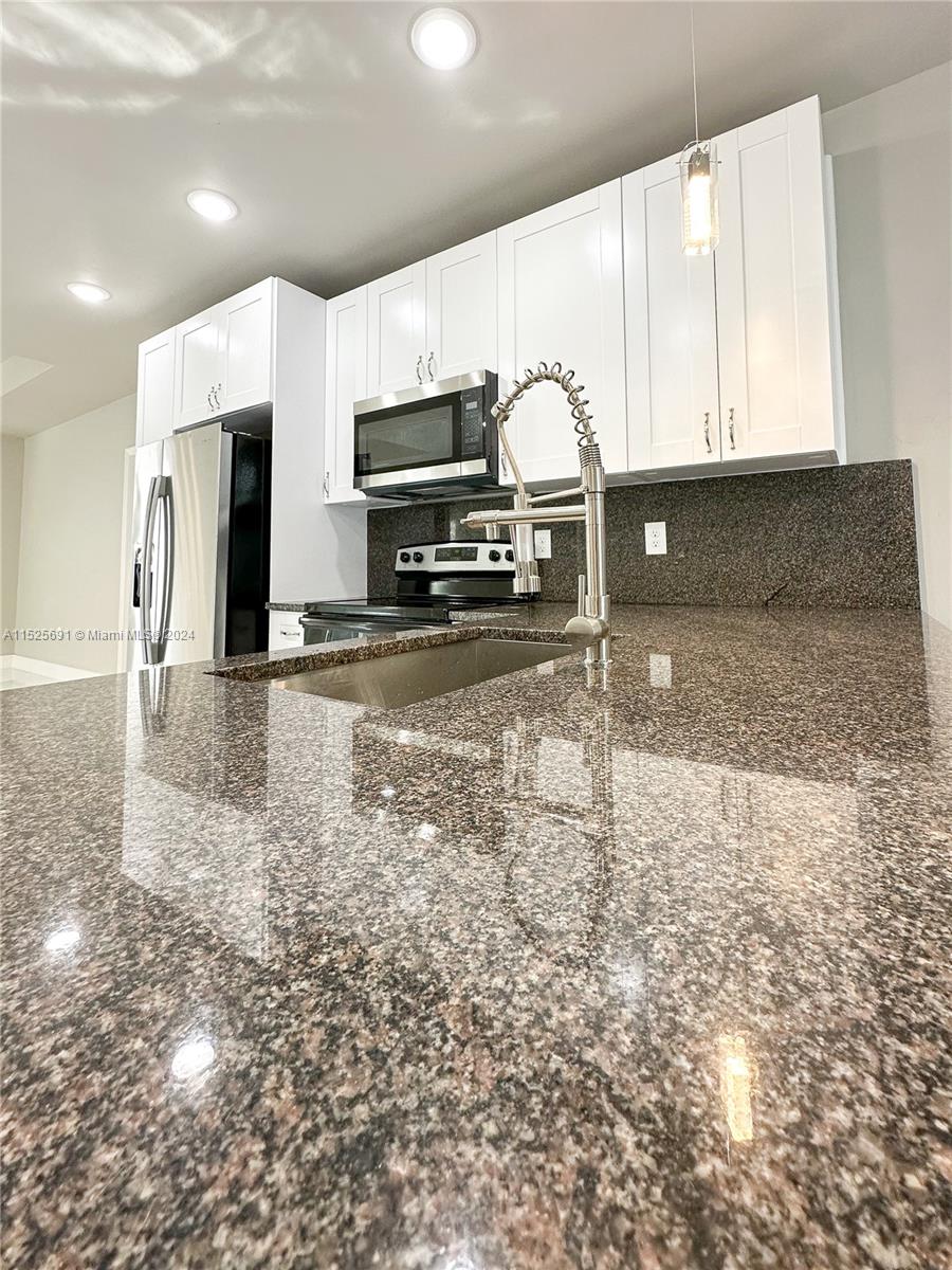 828 Homestead Road South Lehigh Acres, FL 33974 - Photo 7 of 48 a open kitchen with stainless steel appliances kitchen island granite countertop a sink and cabinets
