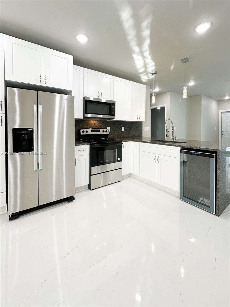 828 Homestead Road South Lehigh Acres, FL 33974 - Photo 9 of 48 a large kitchen with stainless steel appliances a refrigerator a sink a stove a microwave and island