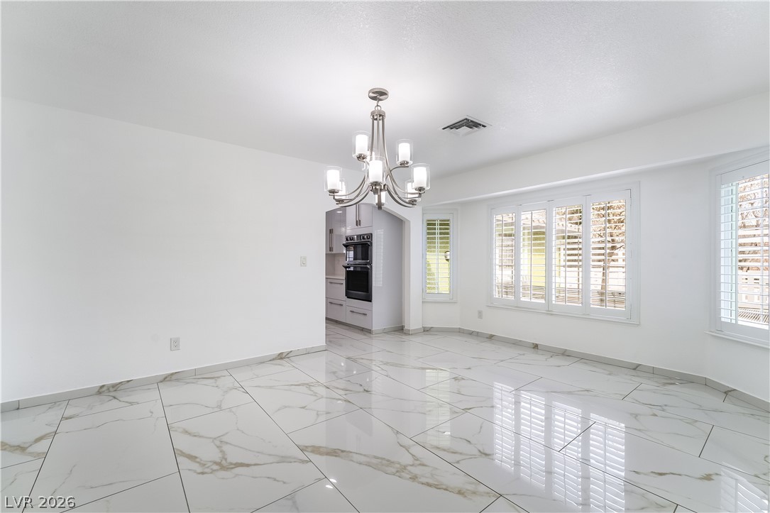 3160 East Viking Road Las Vegas, NV 89121 - Photo 34 of 99 Spare room with a chandelier and light marble finish flooring