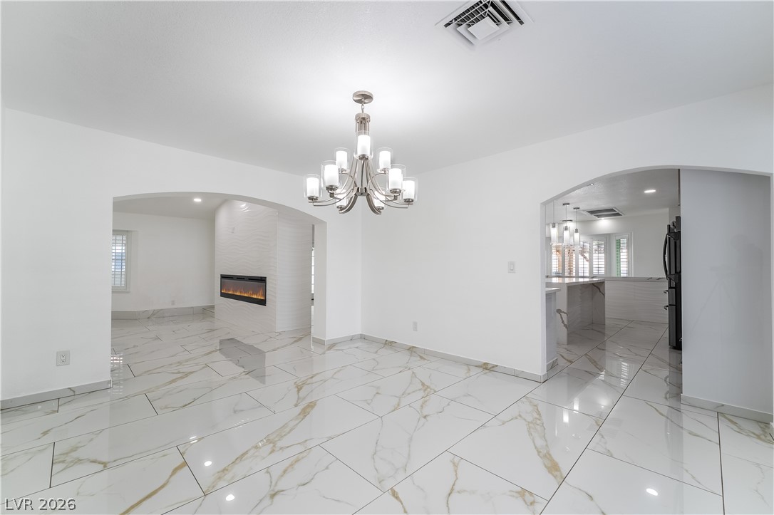 3160 East Viking Road Las Vegas, NV 89121 - Photo 36 of 99 Unfurnished dining area featuring arched walkways, a large fireplace, and a chandelier