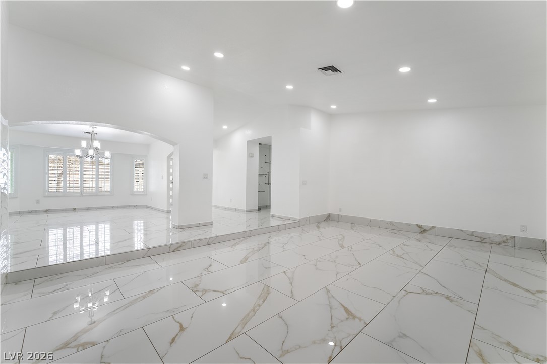 3160 East Viking Road Las Vegas, NV 89121 - Photo 38 of 99 Spare room featuring arched walkways, hanging lights, and light marble finish flooring