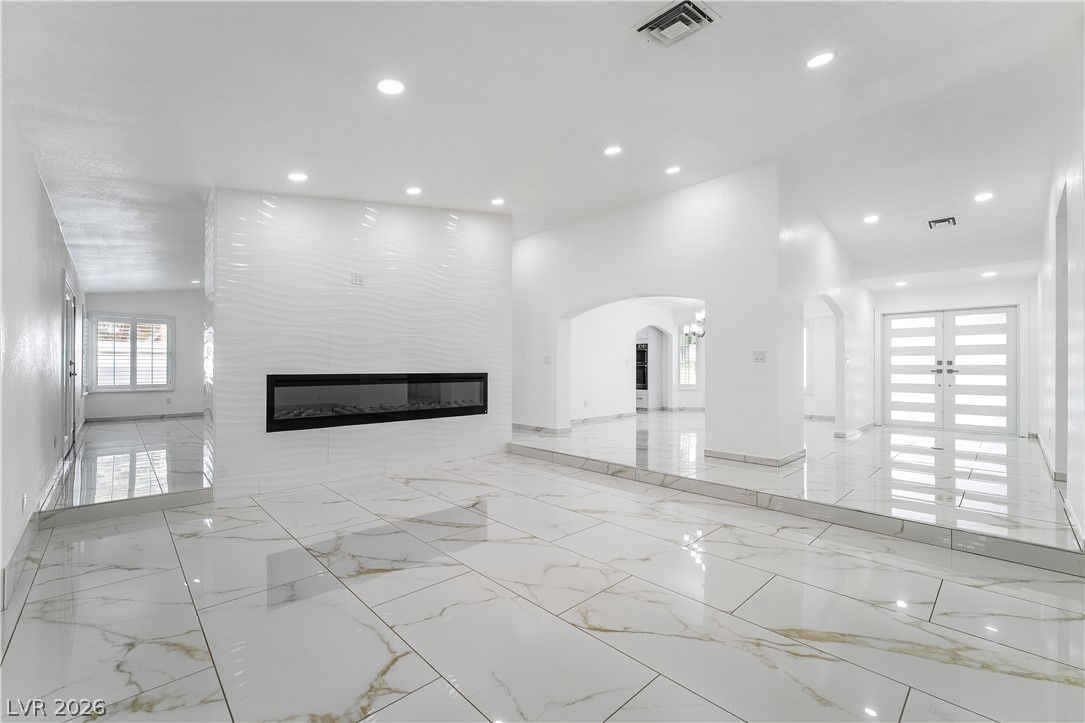3160 East Viking Road Las Vegas, NV 89121 - Photo 39 of 99 Unfurnished living room featuring healthy amount of natural light, a large fireplace, light marble finish flooring, and recessed lighting