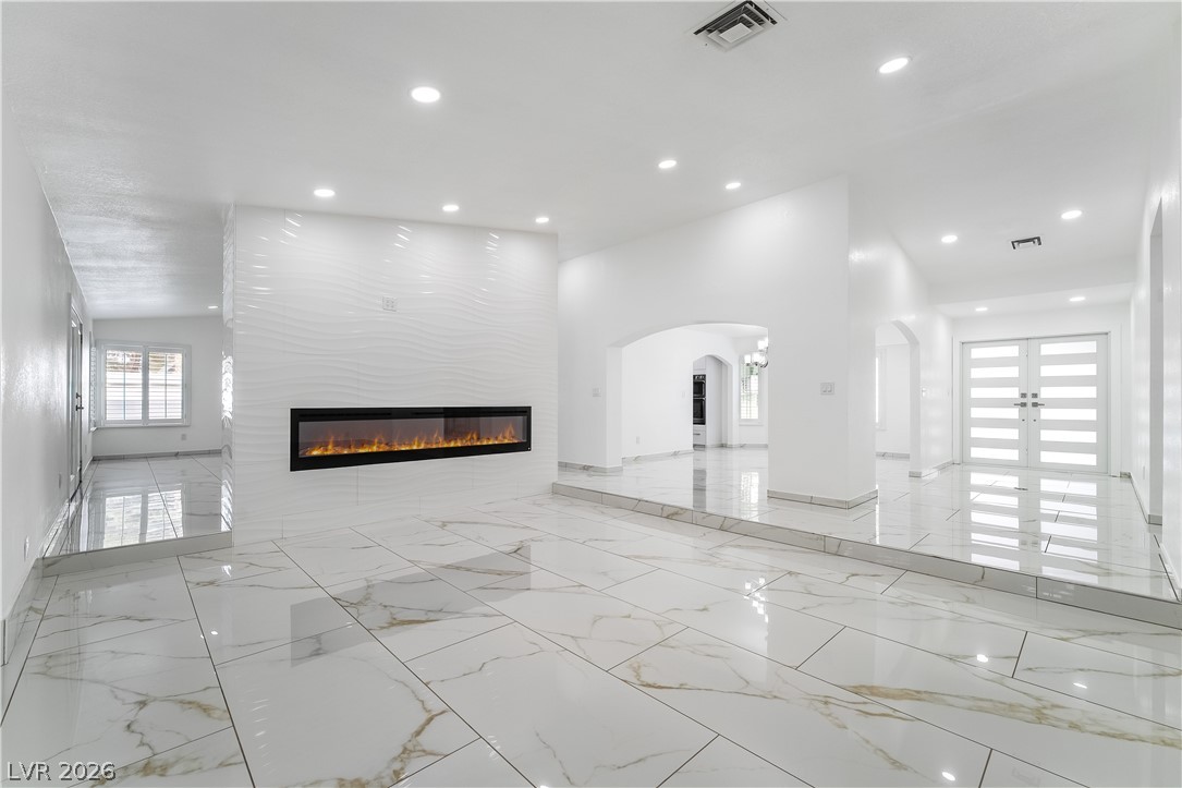 3160 East Viking Road Las Vegas, NV 89121 - Photo 40 of 99 Unfurnished living room featuring light marble finish floors, arched walkways, recessed lighting, and a large fireplace