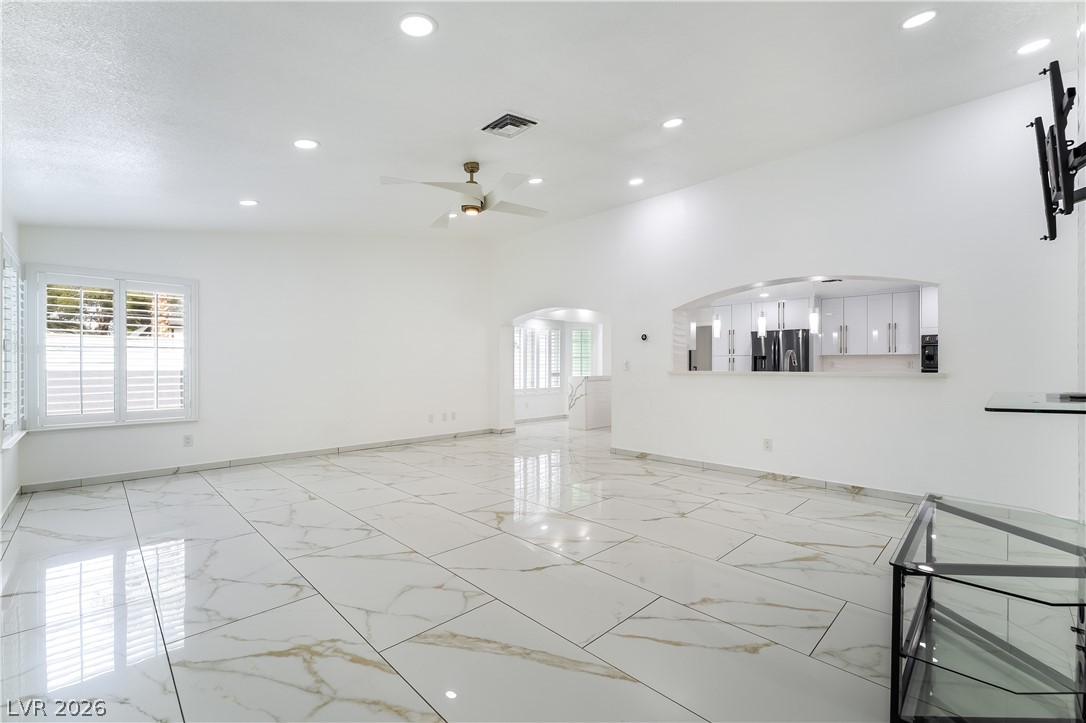 3160 East Viking Road Las Vegas, NV 89121 - Photo 41 of 99 Unfurnished living room with arched walkways, a ceiling fan, light marble finish flooring, and recessed lighting