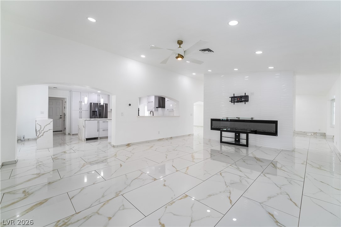 3160 East Viking Road Las Vegas, NV 89121 - Photo 42 of 99 Unfurnished living room with arched walkways, a ceiling fan, and recessed lighting
