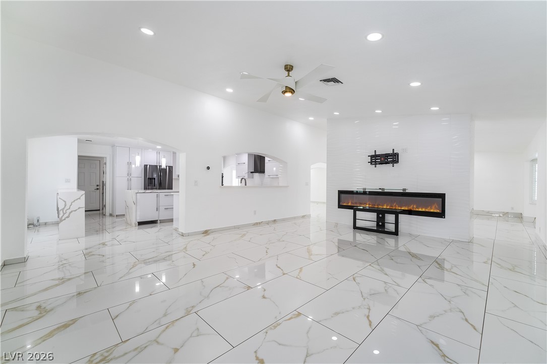 3160 East Viking Road Las Vegas, NV 89121 - Photo 44 of 99 Unfurnished living room with arched walkways, a fireplace, a ceiling fan, and recessed lighting