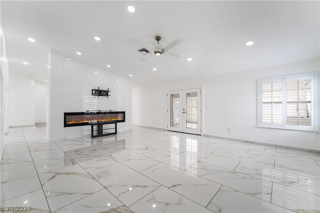 3160 East Viking Road Las Vegas, NV 89121 - Photo 46 of 99 Unfurnished living room featuring french doors, ceiling fan, a fireplace, recessed lighting, and vaulted ceiling