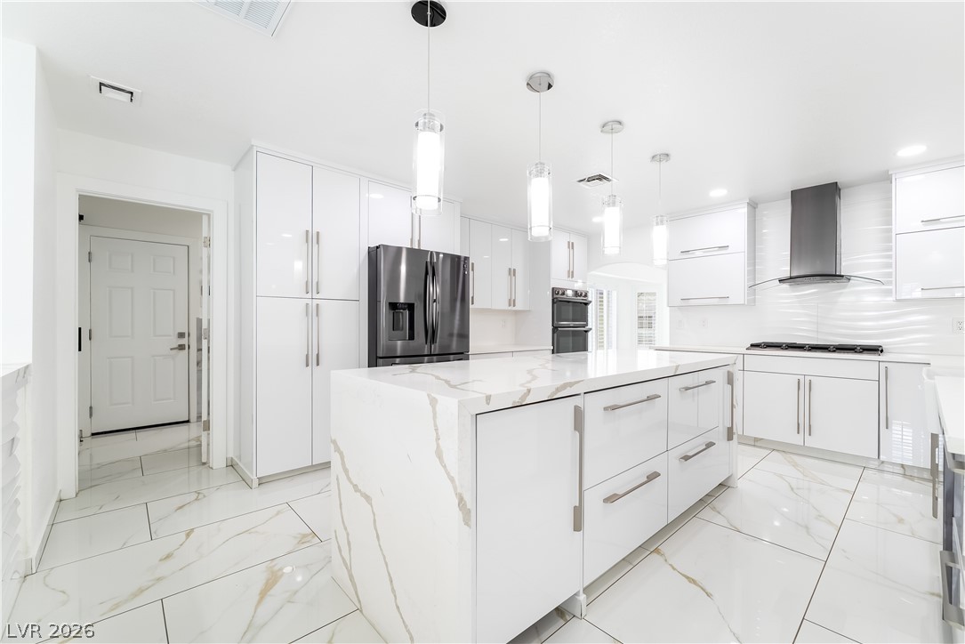3160 East Viking Road Las Vegas, NV 89121 - Photo 48 of 99 Kitchen featuring hanging light fixtures, a kitchen island, white cabinetry, light stone countertops, and stainless steel appliances