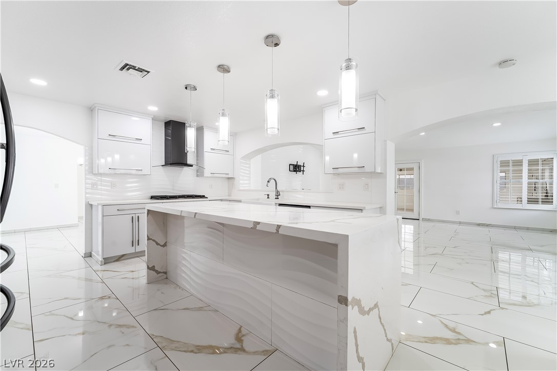 3160 East Viking Road Las Vegas, NV 89121 - Photo 50 of 99 Kitchen with arched walkways, white cabinetry, a kitchen island, light stone countertops, and modern cabinets