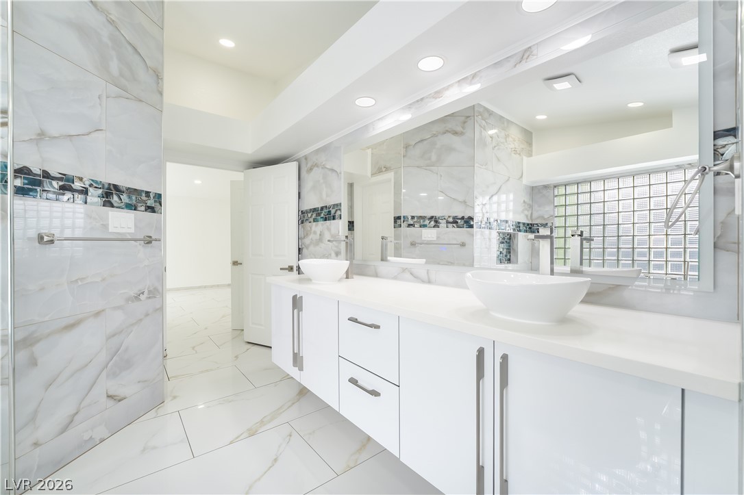 3160 East Viking Road Las Vegas, NV 89121 - Photo 61 of 99 Full bathroom with double vanity, tile walls, light marble finish flooring, and recessed lighting