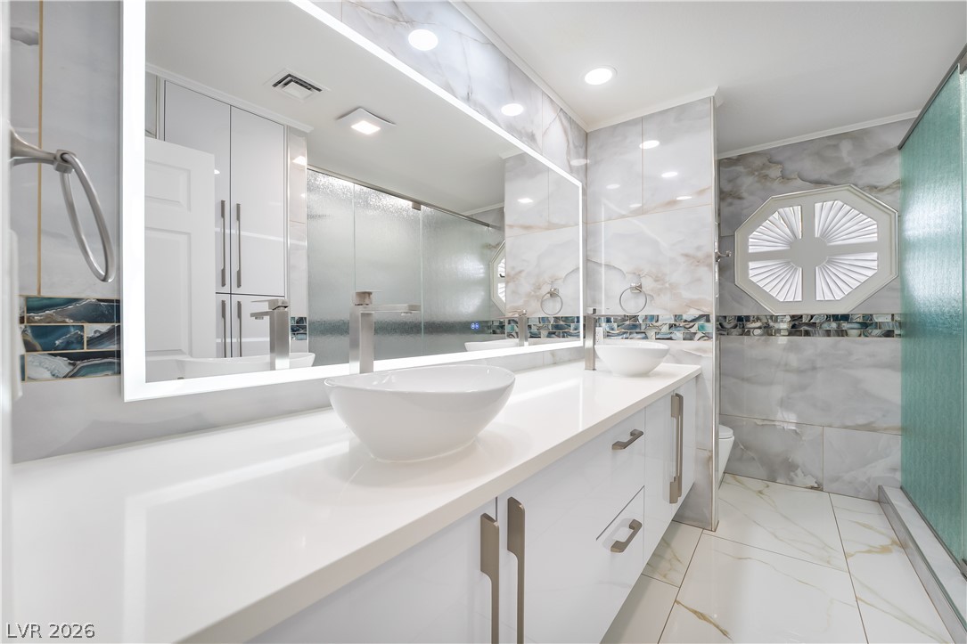 3160 East Viking Road Las Vegas, NV 89121 - Photo 65 of 99 Bathroom with tile walls, double vanity, light marble finish floors, an enclosed shower, and recessed lighting