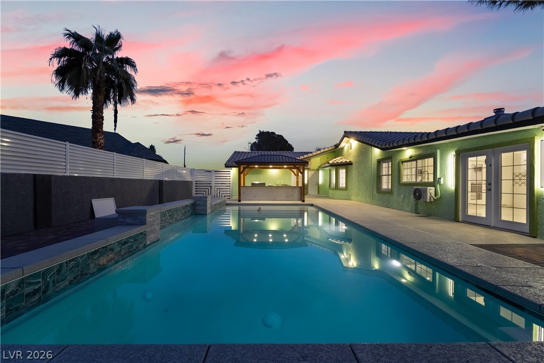 3160 East Viking Road Las Vegas, NV 89121 - Photo 95 of 99 Pool at dusk with french doors, a gazebo, a patio, and a fenced backyard