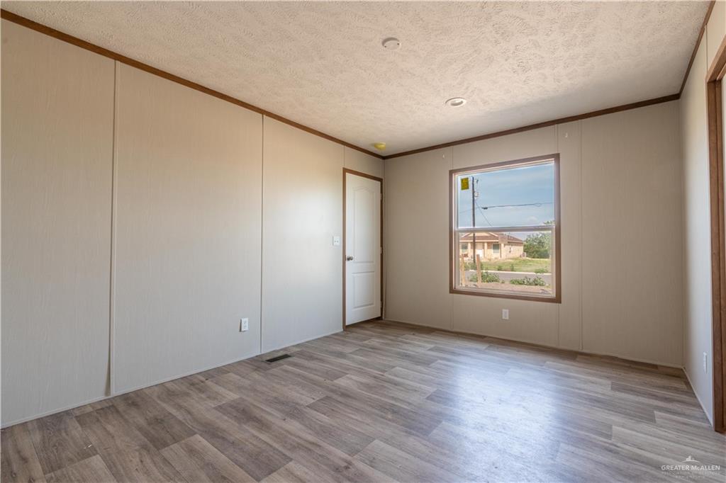 36042 Ranch Park Road San Benito, TX 78586 - Photo 13 of 25 a view of an empty room with wooden floor and a window