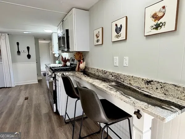 a kitchen with stainless steel appliances granite countertop a stove top oven a sink a dining table and chairs with wooden floor