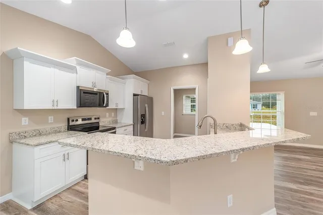 a kitchen with granite countertop a sink a counter top space appliances and cabinets