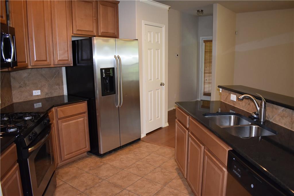 1310 West Parmer Lane, Unit 1503 Austin, TX 78727 - Photo 2 of 26 Kitchen with dark stone countertops, stainless steel appliances, decorative backsplash, and wood finish cabinets