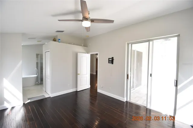 an empty room with wooden floor fan and windows
