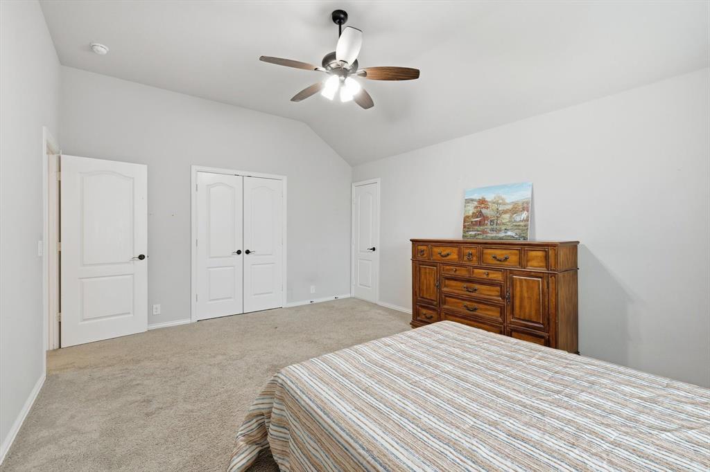 924 Timber Ridge Drive Justin, TX 76247 - Photo 31 of 32 Carpeted room featuring a vaulted ceiling with a ceiling fan, two paneled doors, and a double-door closet