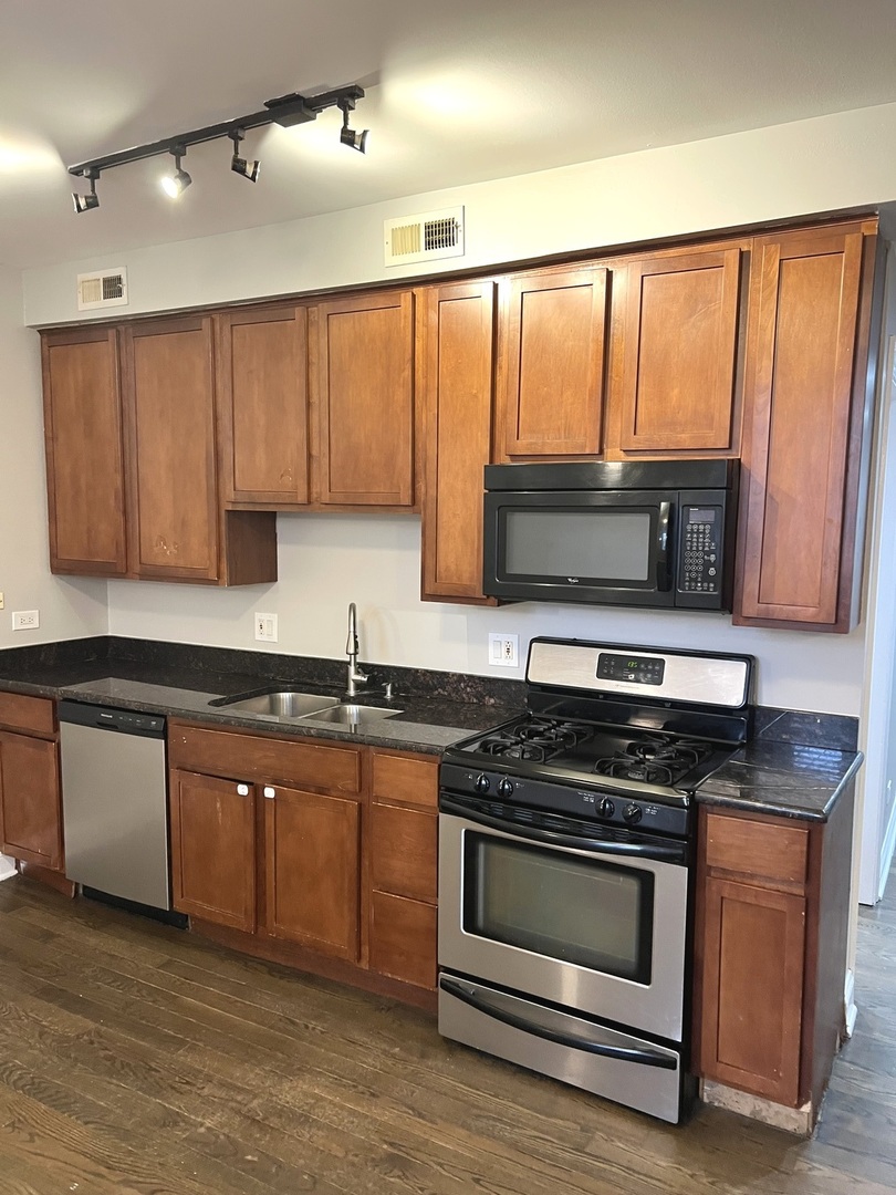 2254 West Arthur Avenue, Unit 1051A Chicago, IL 60645 - Photo 4 of 20 a kitchen with granite countertop a stove top oven microwave and cabinets
