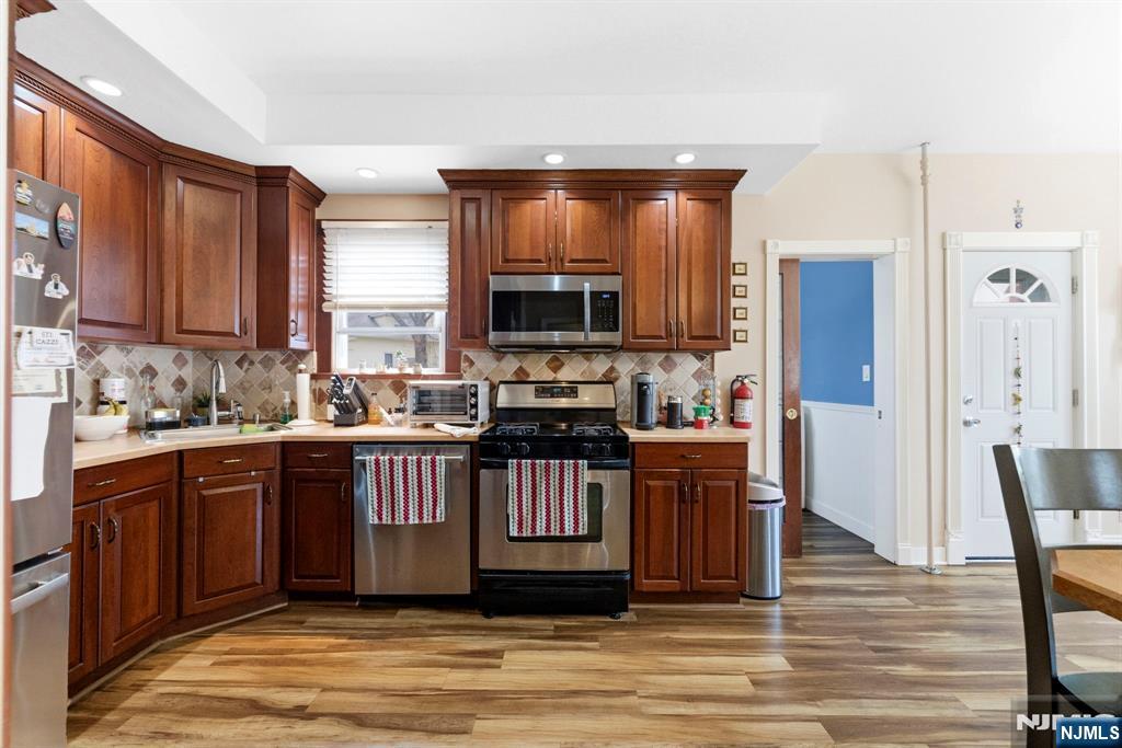 48 Rochelle Avenue Rochelle Park, NJ 07662 - Photo 11 of 30 a kitchen with stainless steel appliances granite countertop a stove a sink dishwasher a refrigerator and a microwave oven on the wooden floor