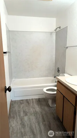 a bathroom with a granite countertop bathtub shower sink vanity and toilet