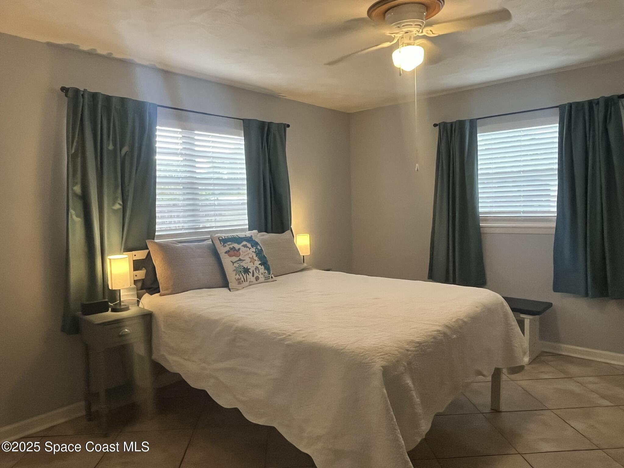 415 Madison Avenue, Unit I102 Cape Canaveral, FL 32920 - Photo 13 of 29 a bedroom with a bed and a chandelier