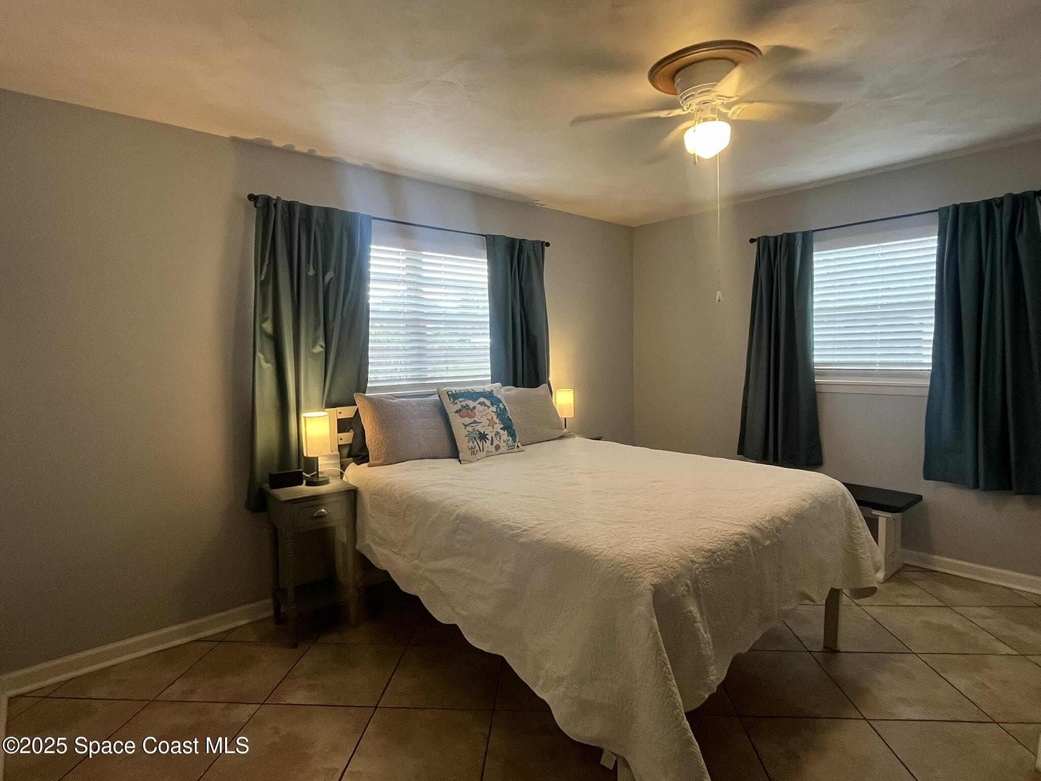 415 Madison Avenue, Unit I102 Cape Canaveral, FL 32920 - Photo 15 of 29 a bedroom with a bed and a chandelier