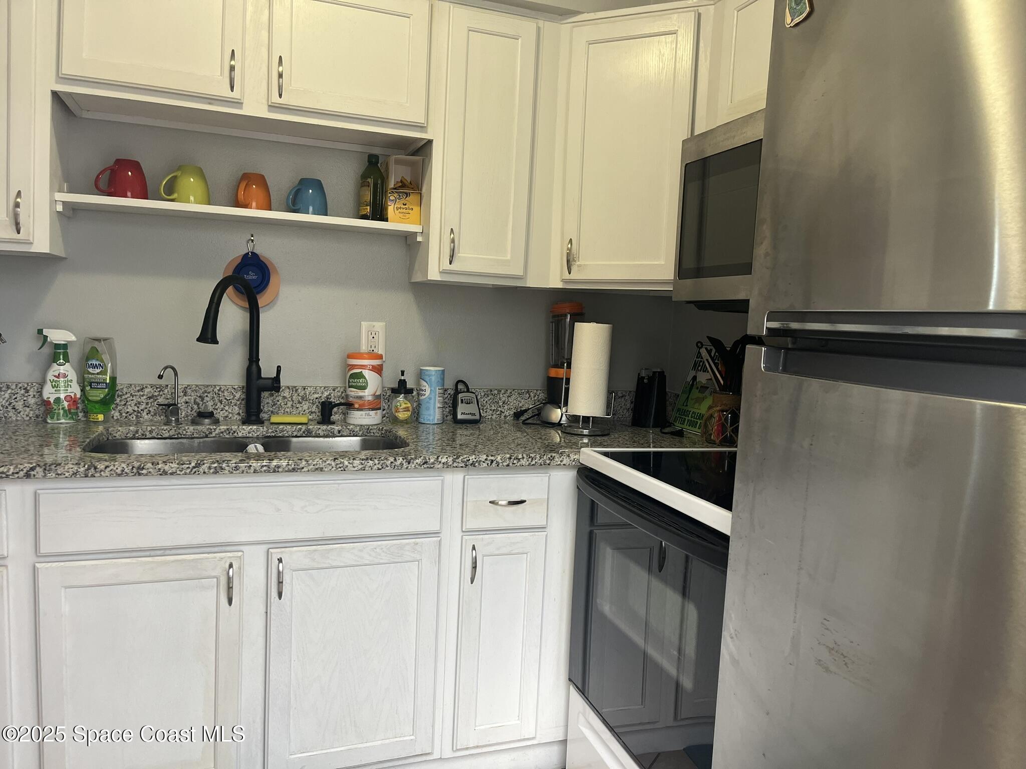 415 Madison Avenue, Unit I102 Cape Canaveral, FL 32920 - Photo 22 of 29 a kitchen with stainless steel appliances granite countertop white cabinets and a sink