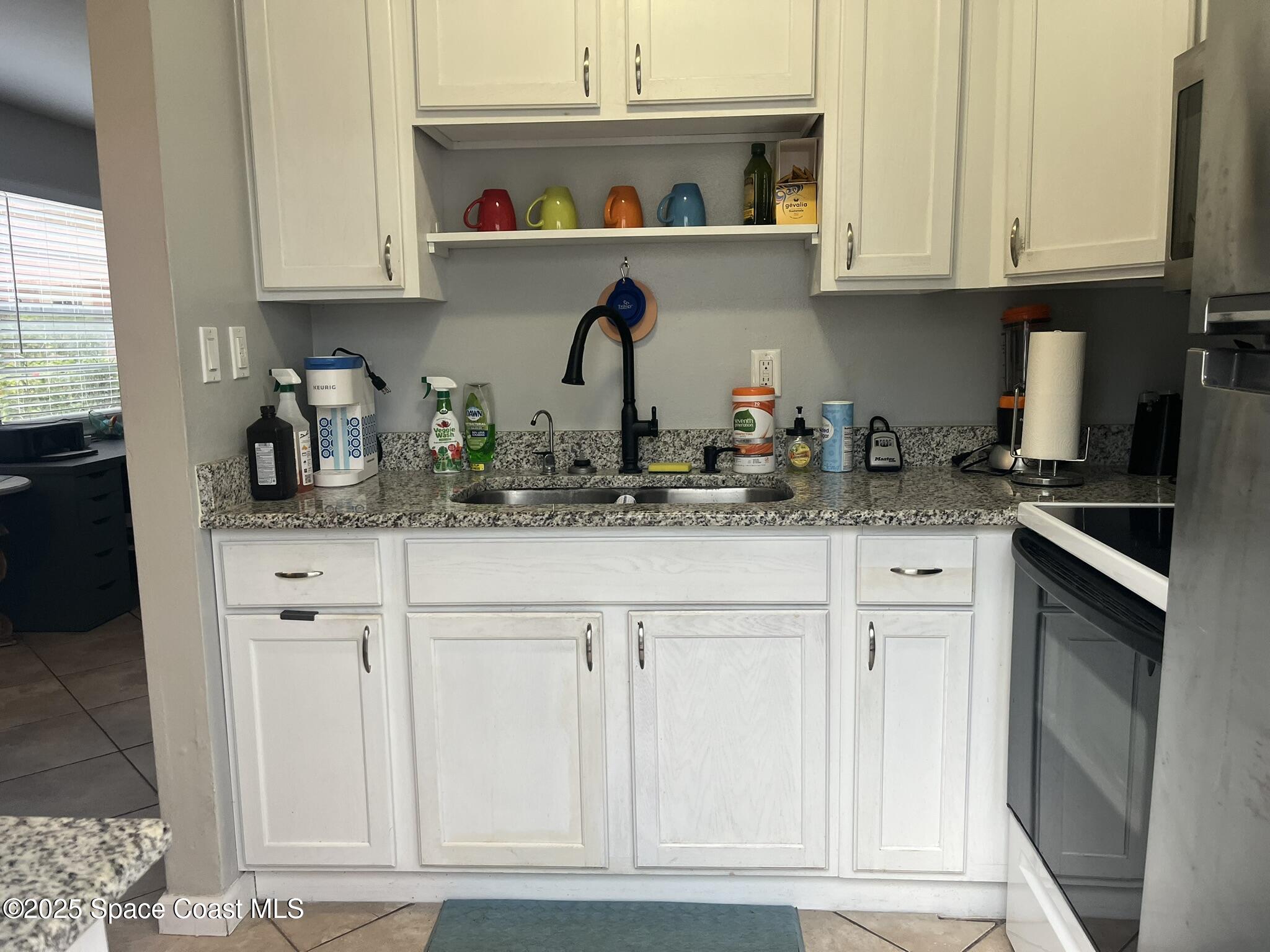 415 Madison Avenue, Unit I102 Cape Canaveral, FL 32920 - Photo 6 of 29 a kitchen with white cabinets and sink