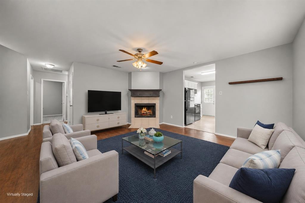 834 Hazel's Way Anna, TX 75409 - Photo 5 of 21 Living room featuring a corner fireplace with a tile surround and wood mantel, wood-finish flooring, and a ceiling fan