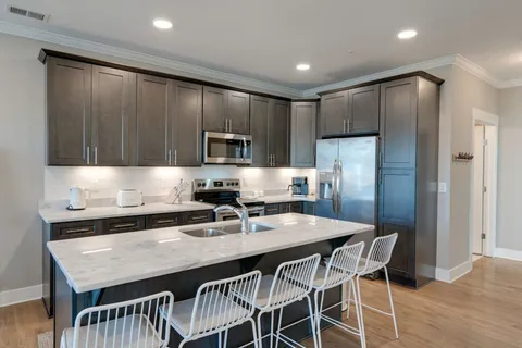 a kitchen with stainless steel appliances a table chairs refrigerator and microwave