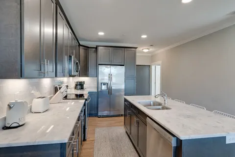 a kitchen with kitchen island granite countertop stainless steel appliances a sink stove and refrigerator