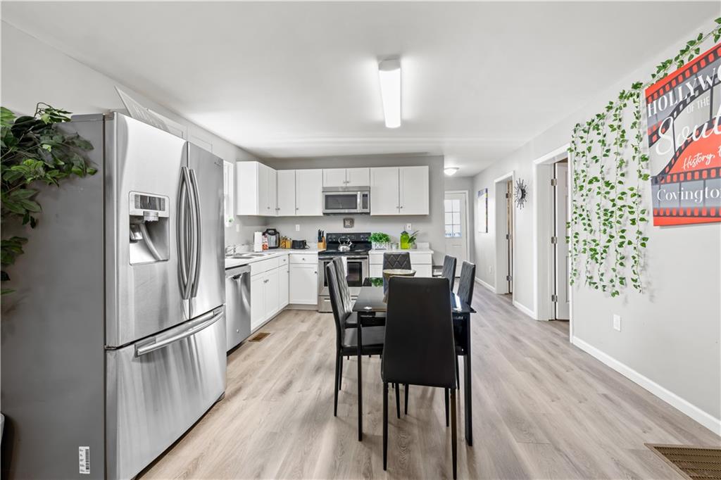 2220 Lee Street Southwest Covington, GA 30014 - Photo 4 of 30 a kitchen with stainless steel appliances a refrigerator a stove a dining table and chairs