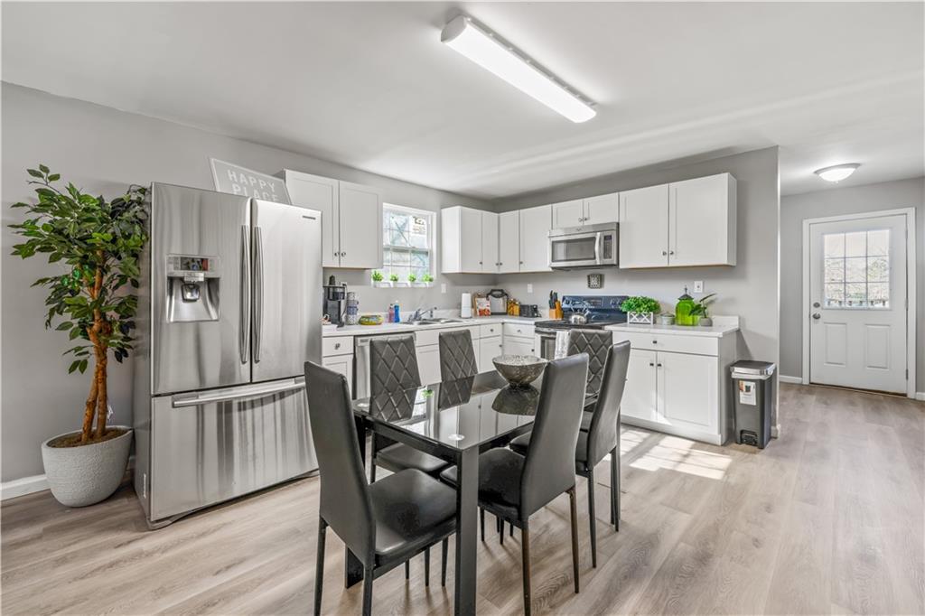 2220 Lee Street Southwest Covington, GA 30014 - Photo 7 of 30 a kitchen with stainless steel appliances a refrigerator a stove a sink dishwasher and white cabinets with wooden floor