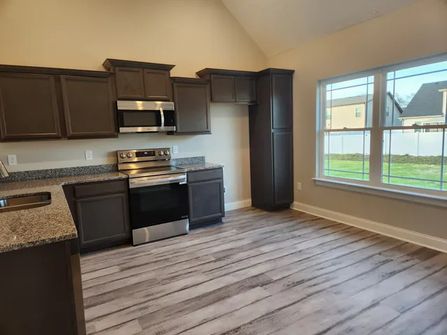 a kitchen with granite countertop a refrigerator and a stove top oven