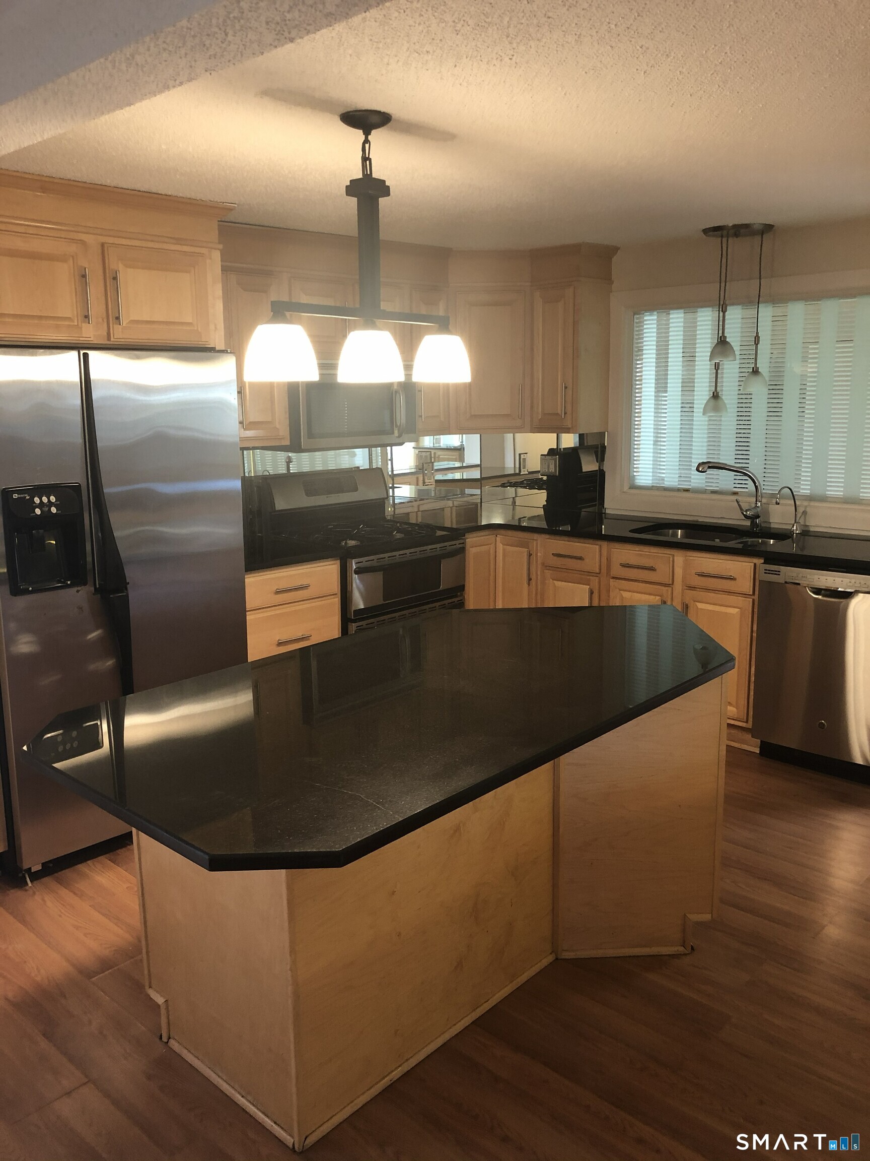 a kitchen with stainless steel appliances granite countertop a sink a stove and a refrigerator
