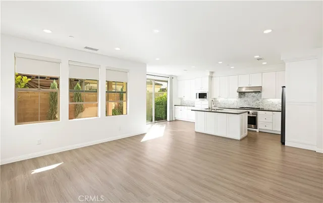 a large white kitchen with wooden floors and white walls