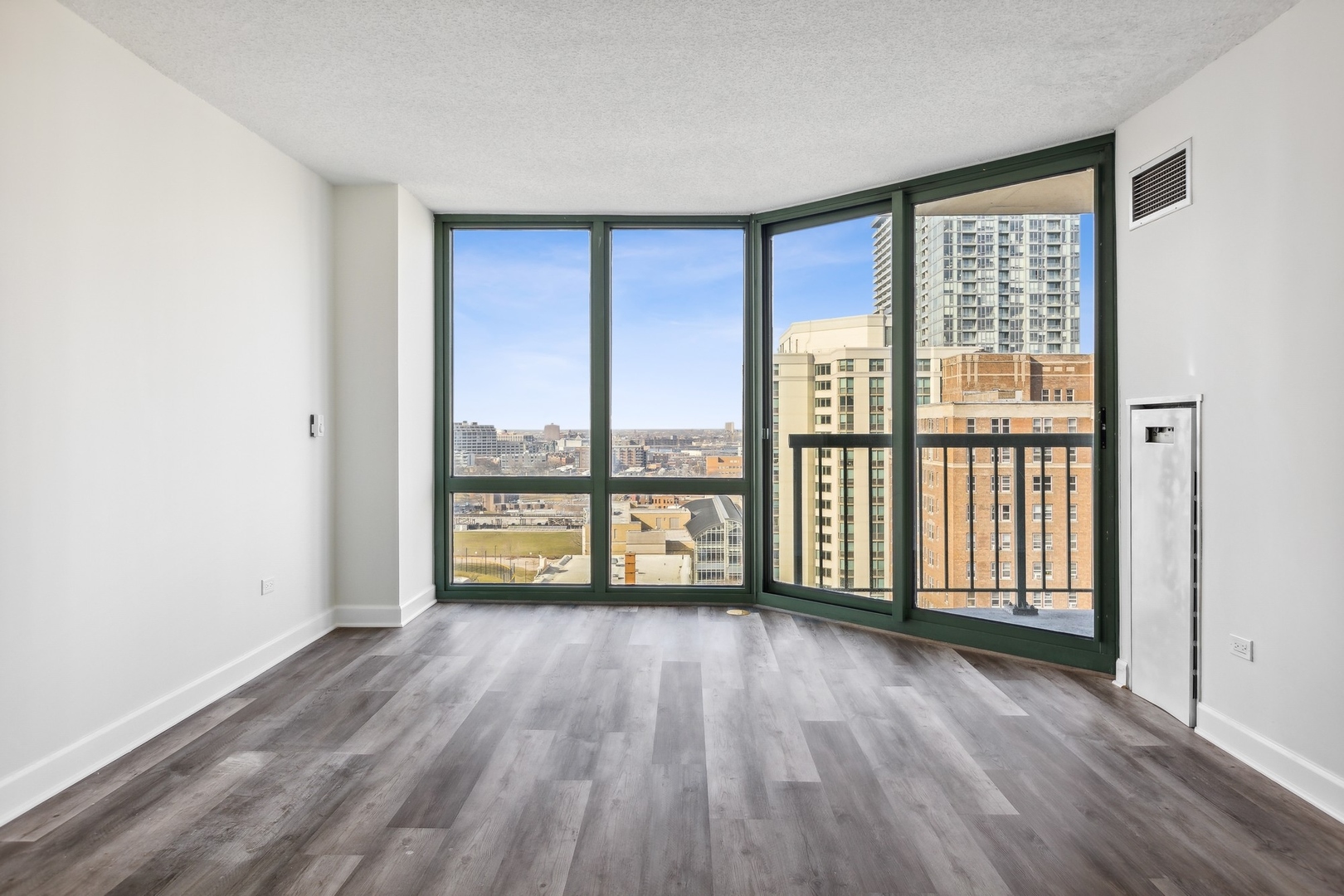 111 West Maple Street, Unit 1208 Chicago, IL 60610 - Photo 4 of 14 a view of an empty room with wooden floor and a window
