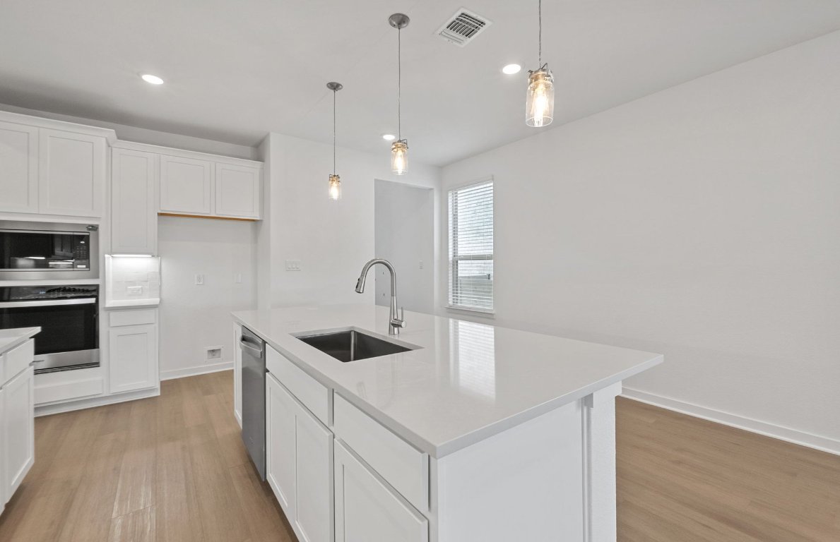 1700 Spg Mountain Cove Georgetown, TX 78628 - Photo 9 of 40 a kitchen with stainless steel appliances granite countertop a sink a oven a refrigerator and white cabinets with wooden floor